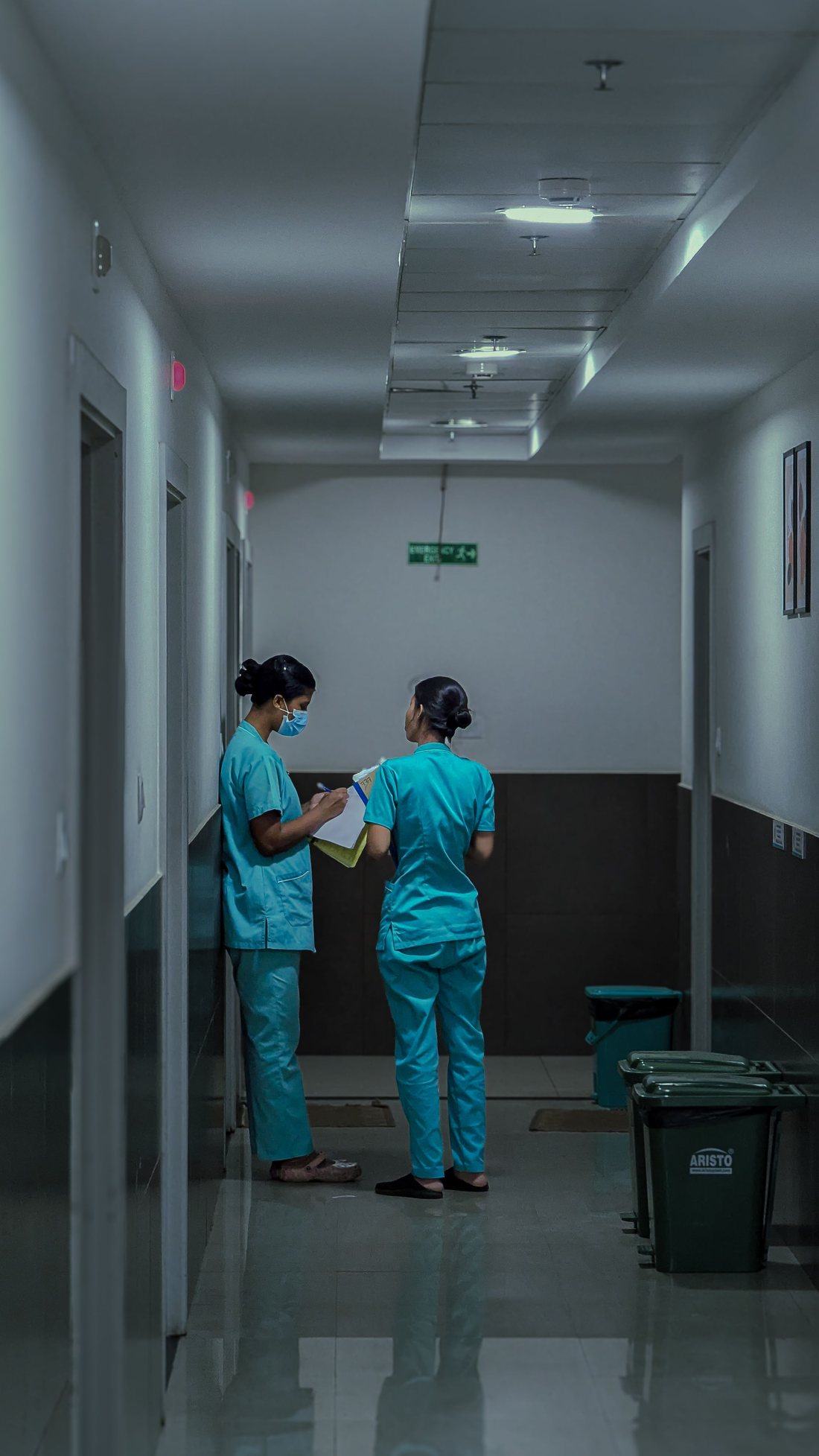 Two nurses coordinating in a hospital corridor